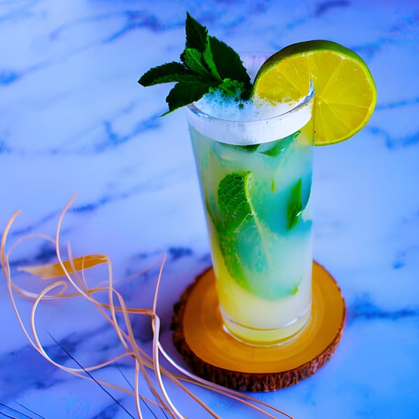 A refreshing mojito cocktail from 101 Kitchen, garnished with mint and a lime slice on a wooden coaster.